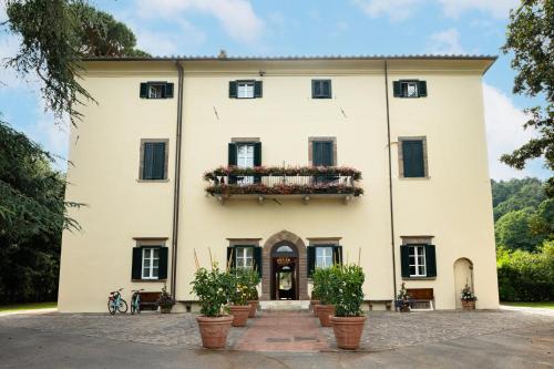 a large white building with potted plants in front of it at Hotel Villa San Michele in Lucca
