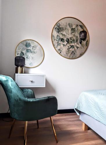a bedroom with a green chair and two mirrors at Apartament w Centrum in Zamość