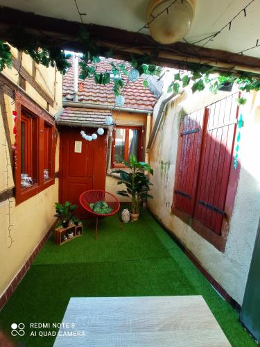 un patio al aire libre con césped verde y puertas rojas en happy petite venise, en Colmar