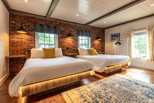 a bedroom with two beds and a brick wall at The Barnstead Inn in Manchester Center