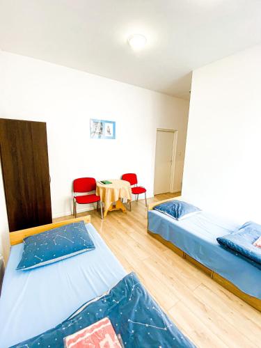 two beds in a room with a table and chairs at Schronisko Młodzieżowe PTSM "Alko" in Rzeszów