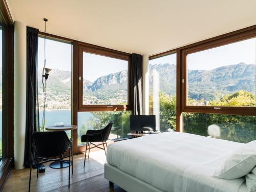a bedroom with a large bed and large windows at Casa Sull'Albero in Malgrate