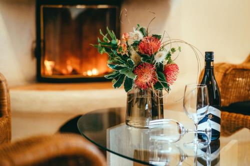 een glazen tafel met een vaas met bloemen en een fles wijn bij Landhotel Classic in Wensickendorf