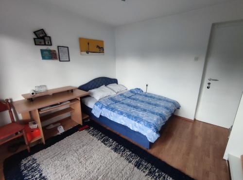 1 dormitorio con cama, escritorio y alfombra en Cozy room with a balcony en Sarajevo