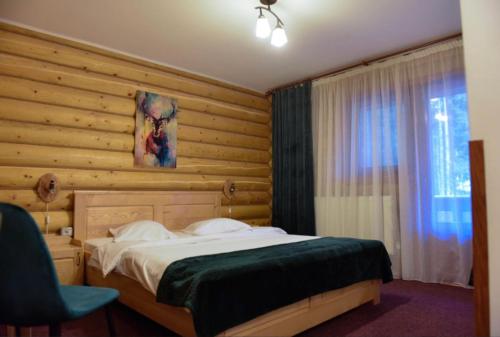 a bedroom with a bed and a wooden wall at Pensiunea Vanatorul in Obarsia-Lotrului