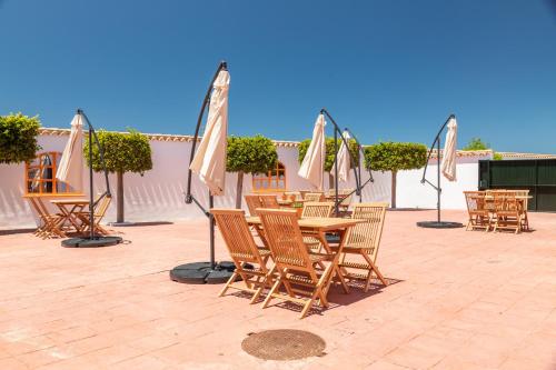 a group of chairs and tables with umbrellas on a patio at Hotel Marhava in Conil de la Frontera
