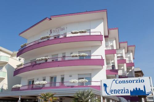 a tall white building with purple balconies at Hotel Telenia in Lido di Jesolo