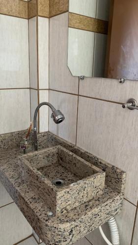 a stone sink in a bathroom with a mirror at Hotel Dom Daniel in Palmares