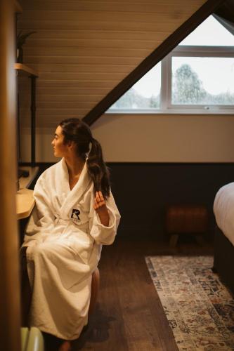 a woman in a robe sitting in a room at The Rabbit Hotel & Retreat in Templepatrick