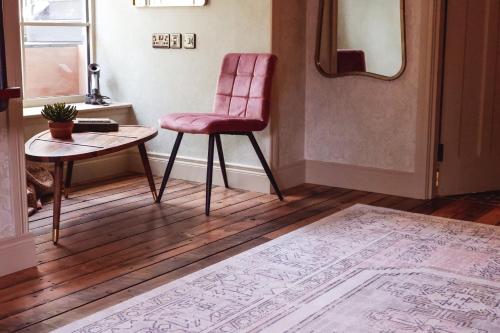 a pink chair and a table in a room at The Rabbit Hotel & Retreat in Templepatrick