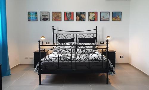 una cama negra en una habitación con fotos en la pared en Casa California en Realmonte