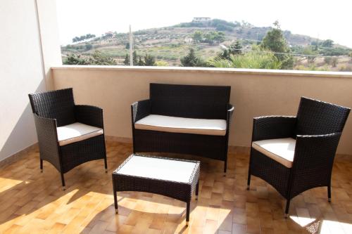 four chairs and a table on a balcony with a window at Casa California in Realmonte
