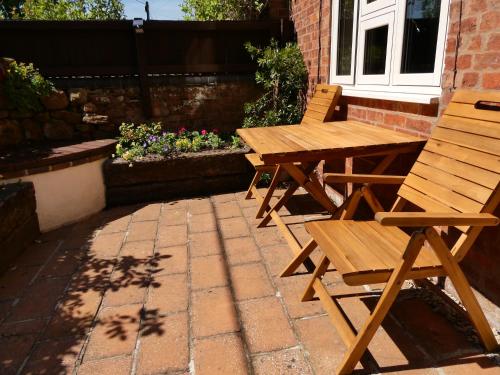una mesa de picnic de madera y sillas en un patio de ladrillo en Fab 2 Bed Cotswolds Cottage with Private Courtyard, 