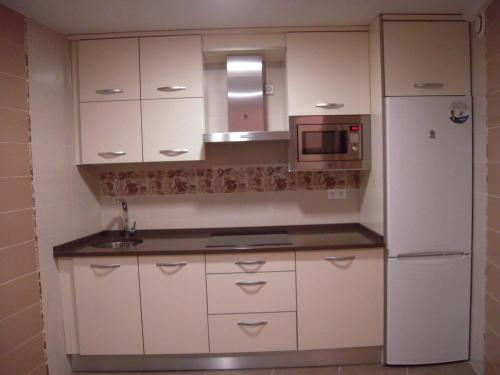 a kitchen with white cabinets and a refrigerator at Casa Rural Carmina in Berlanga de Duero