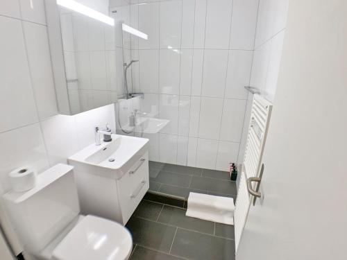 a white bathroom with a toilet and a sink at ARISER - Zug City View 1 Business Apartment in Zug