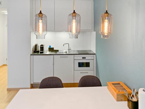 a kitchen with a table and chairs and lights at ARISER - Zug City View 1 Business Apartment in Zug