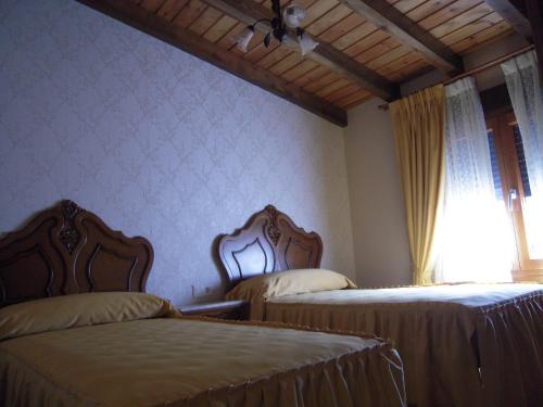1 dormitorio con 2 camas y una ventana con cortinas en Casa Rural Carmina, en Berlanga de Duero