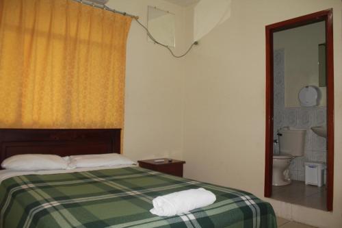 Un dormitorio con una cama verde y blanca y un baño. en Hostal Rosa Mar, en Manta