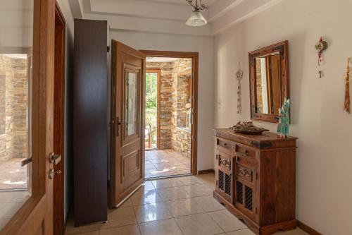 a hallway with a door and a dresser and a mirror at Andros Melissari in Koumárion