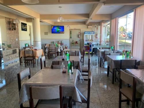 PalmaresHotel Dom Daniel的一间有桌椅和墙上电视的餐厅