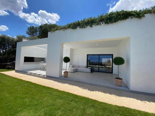 uma casa branca com dois vasos de árvores num relvado em Domo La Vela em Cala Liberotto