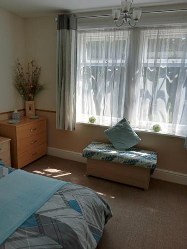 a bedroom with a bed and two windows and a couch at The Shady Corner, Flat 2, 16 Sandy Lane in Prestatyn