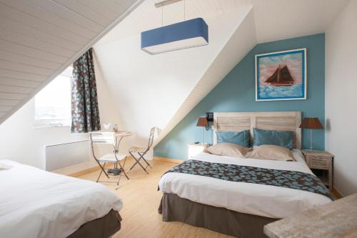 1 dormitorio con 2 camas y mesa. en Hotel Logis Beauséjour, en Erquy