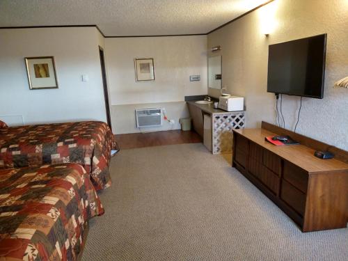 a hotel room with a bed and a flat screen tv at Budget Host 4U Motel in Bowman