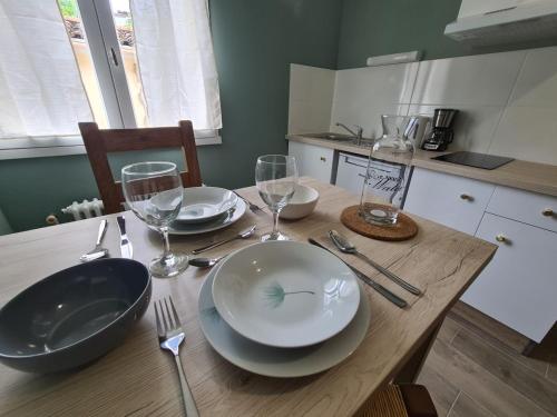 une table en bois avec des assiettes et des verres à vin dessus dans l'établissement Studio LA TERRAZA, à Lamalou-les-Bains