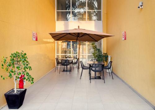 a patio with tables and chairs and an umbrella at City Express by Marriott Tepotzotlán in Tepotzotlán