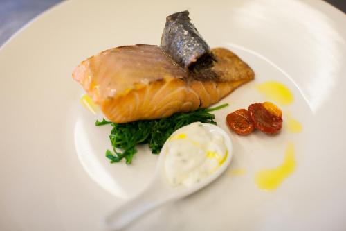 a white plate with a piece of fish and a spoon at Sartori's Hotel in Trento