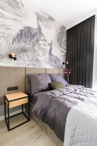 a bedroom with a bed and a wall with a peacock mural at Apartament Voila in Warsaw
