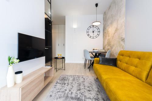 sala de estar con sofá amarillo y TV en Apartament Voila, en Varsovia