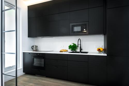 a kitchen with black cabinets and a sink at Apartament Voila in Warsaw