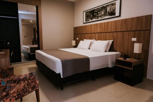 um quarto de hotel com uma cama e uma cadeira em Occitano Apart Hotel em Piracicaba