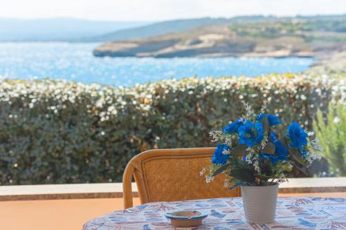 einen Tisch mit einer Vase mit blauen Blumen darauf in der Unterkunft L'Ancora Blu in Porto Torres