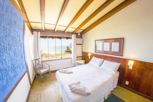 ein Schlafzimmer mit einem großen weißen Bett und einem Fenster in der Unterkunft Pousada La Plage Peró in Cabo Frio
