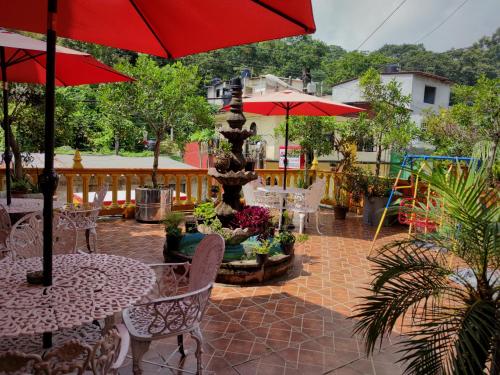 a patio with tables and umbrellas and a fountain at Hotel El Paraiso in Xilitla