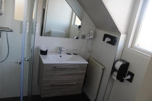 een kleine badkamer met een wastafel en een douche bij Hotel Restaurant 't Klokje in Renesse