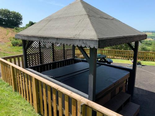 a gazebo with a roof on a deck at Kabin in the woods with Hot Tub in Llandybie