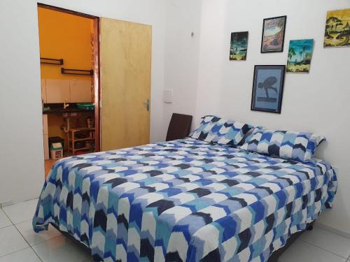 a bedroom with a bed with a blue and white comforter at Casinha na Praia do Guajiru in Guajiru