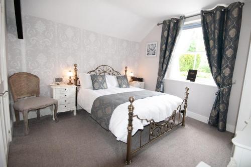 um quarto com uma cama, uma cadeira e uma janela em Exmoor House em Dunster