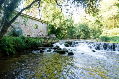 a stream of water with rocks in front of a building at Neiva River House - Azenha Next to the River in Esposende