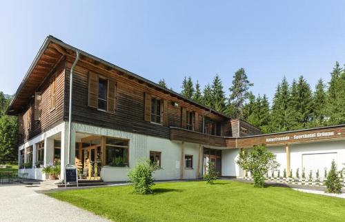 a large wooden house with a green yard at Sporthotel Grünau - Wimmergreuth in Grünau im Almtal
