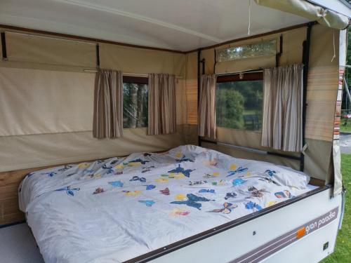 a bed in the back of a caravan at Old Timer Vouwwagen in Tynaarlo