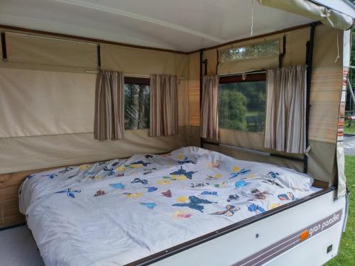 una cama en la parte trasera de una caravana en Old Timer Vouwwagen, en Tynaarlo