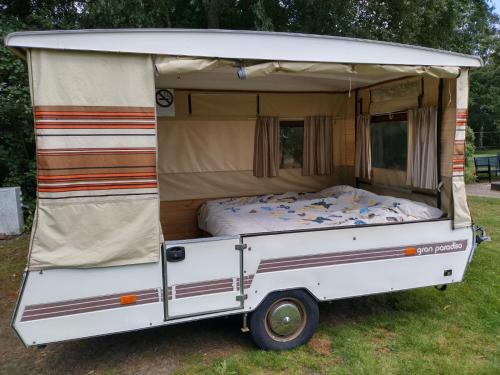 Una caravana blanca con una cama en ella en Old Timer Vouwwagen, en Tynaarlo