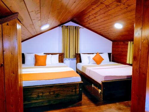 two beds in a room with wooden walls at Moon Plains Luxury Apartments in Nuwara Eliya