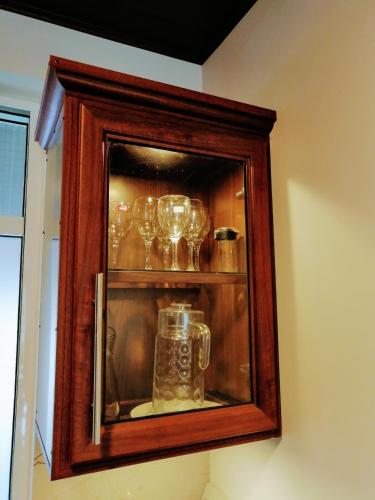 a wooden cabinet with glasses in it at Moon Plains Luxury Apartments in Nuwara Eliya