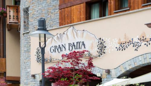 a sign on the side of a building with flowers at Gran Baita Hotel & Wellness in Courmayeur